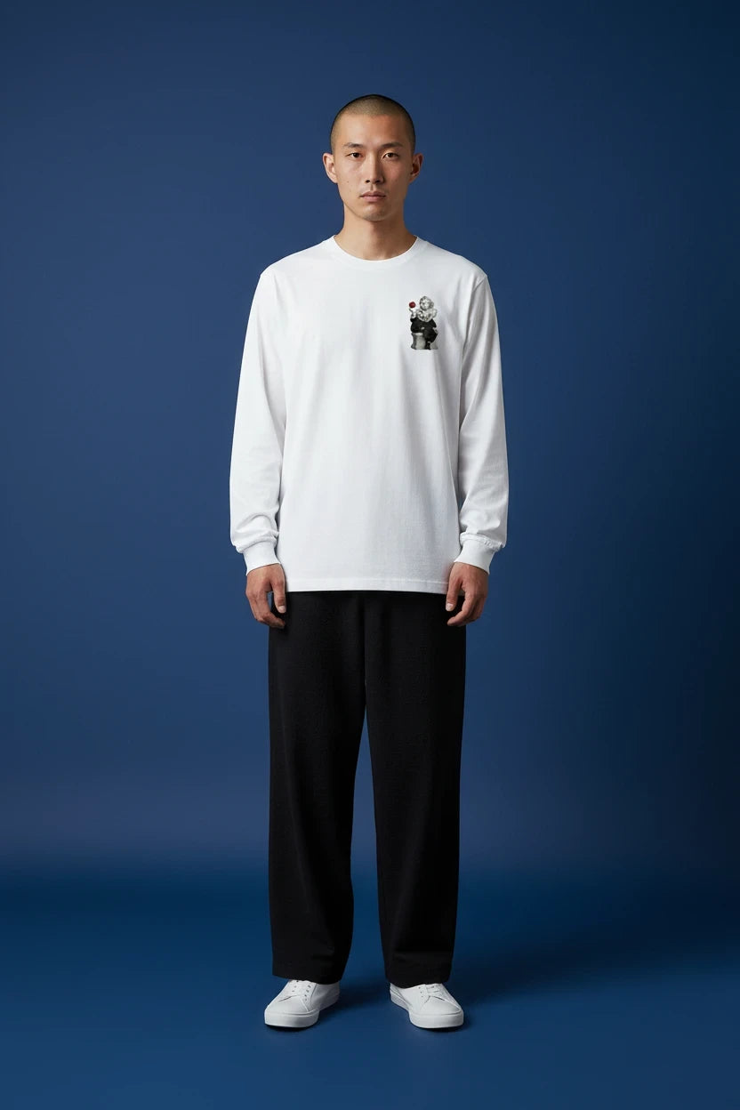 ODD COMMON white long-sleeve t-shirt featuring a small graphic print of a figure with a red cube on the chest